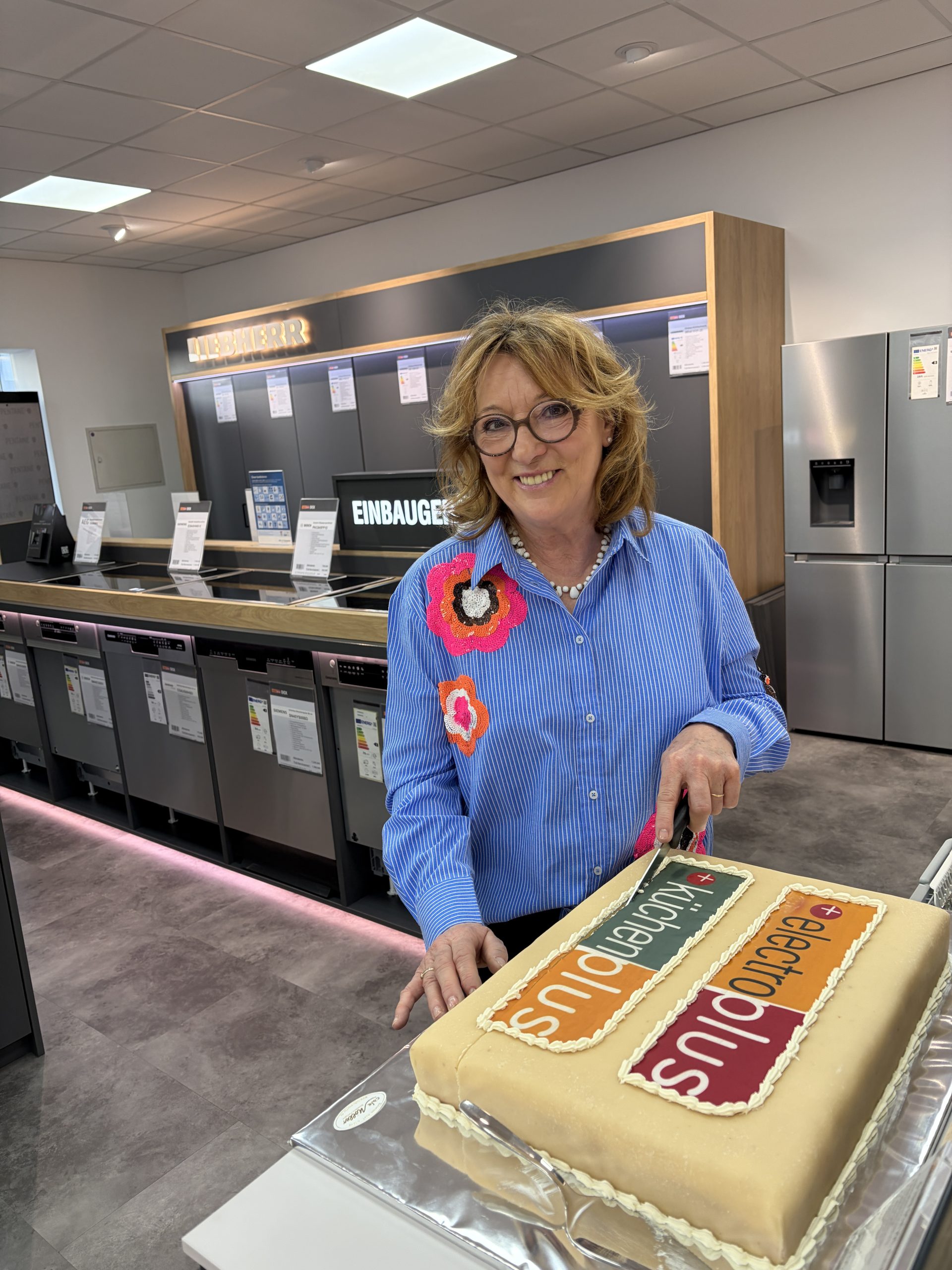 Carmen Dick (electroplus küchenplus Dick) schneidet die electroplus Torte zur Neueröffnung an.