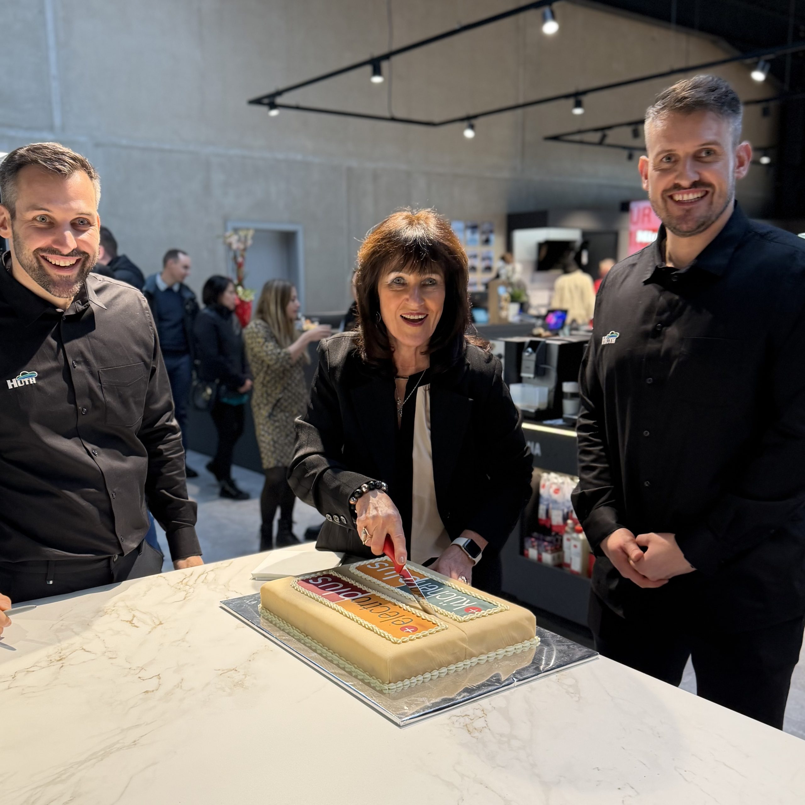 (v. l.) Simon Huth (Geschäftsführer, Hausgeräte Huth), Klaudia Huth (Geschäftsführerin, Hausgeräte Huth) und Aljoscha Huth (Geschäftsführer, Hausgeräte Huth) schneiden zusammen die electroplus Torte zur Neueröffnung an.
